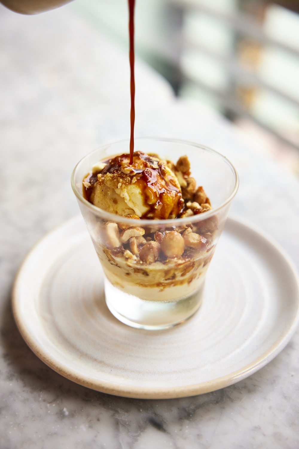 Close-up of an Italian Affogato dessert topped with roasted nuts and a shot of espresso pouring over creamy vanilla ice cream, served at Pizza on the Park, the best Italian restaurant in Bristol for authentic flavours. Captured by David Loftus, this dessert reflects the Italian tradition and quality ingredients Pizza on the Park is known for in Clifton, Bristol."